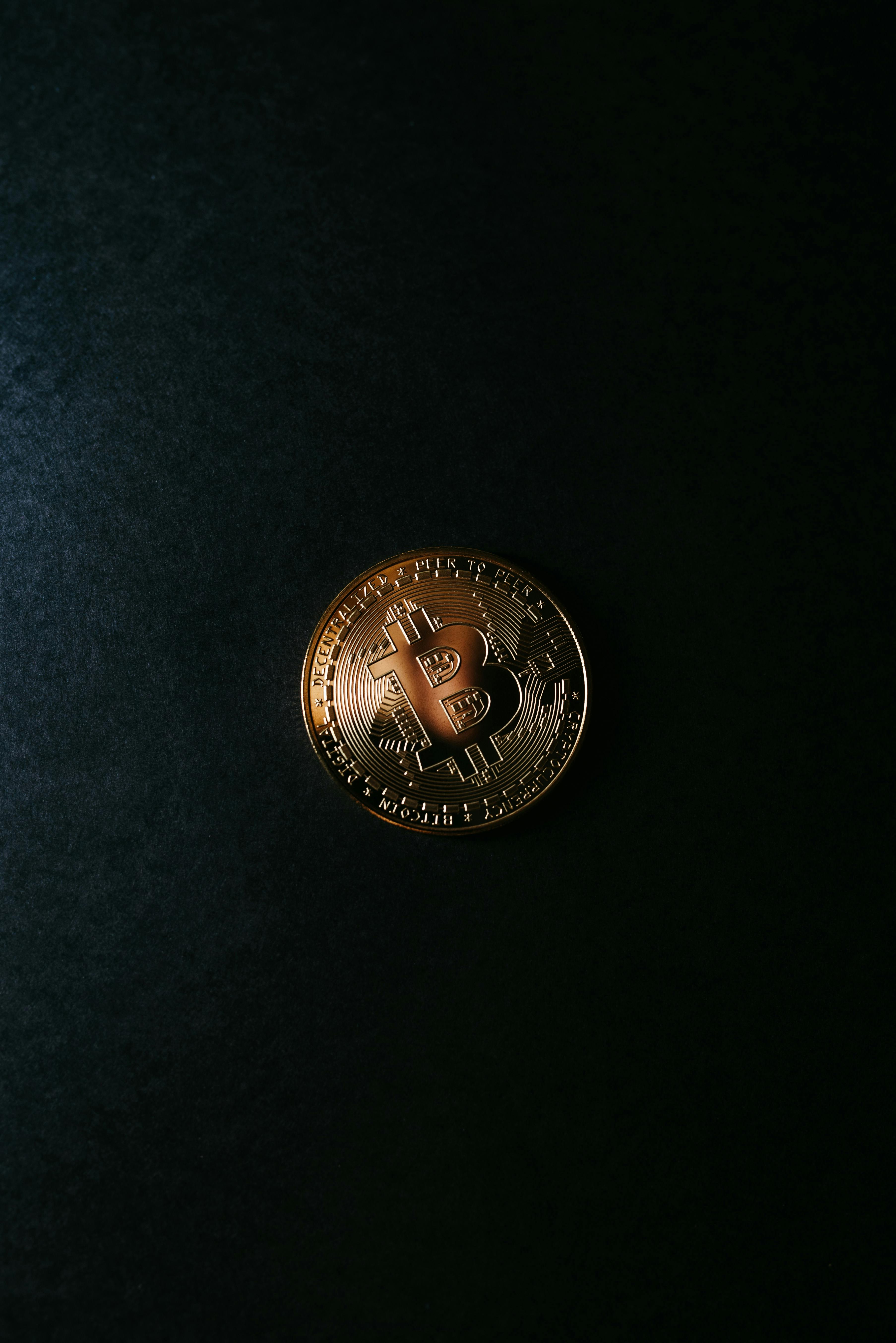 A gold Bitcoin coin placed on a black surface, symbolizing digital currency and blockchain technology.